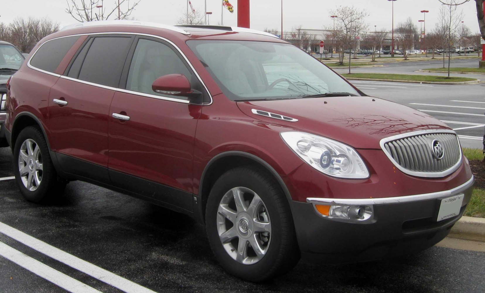 Front side view of a red luxury SUV with distinctive grille and alloy wheels.
