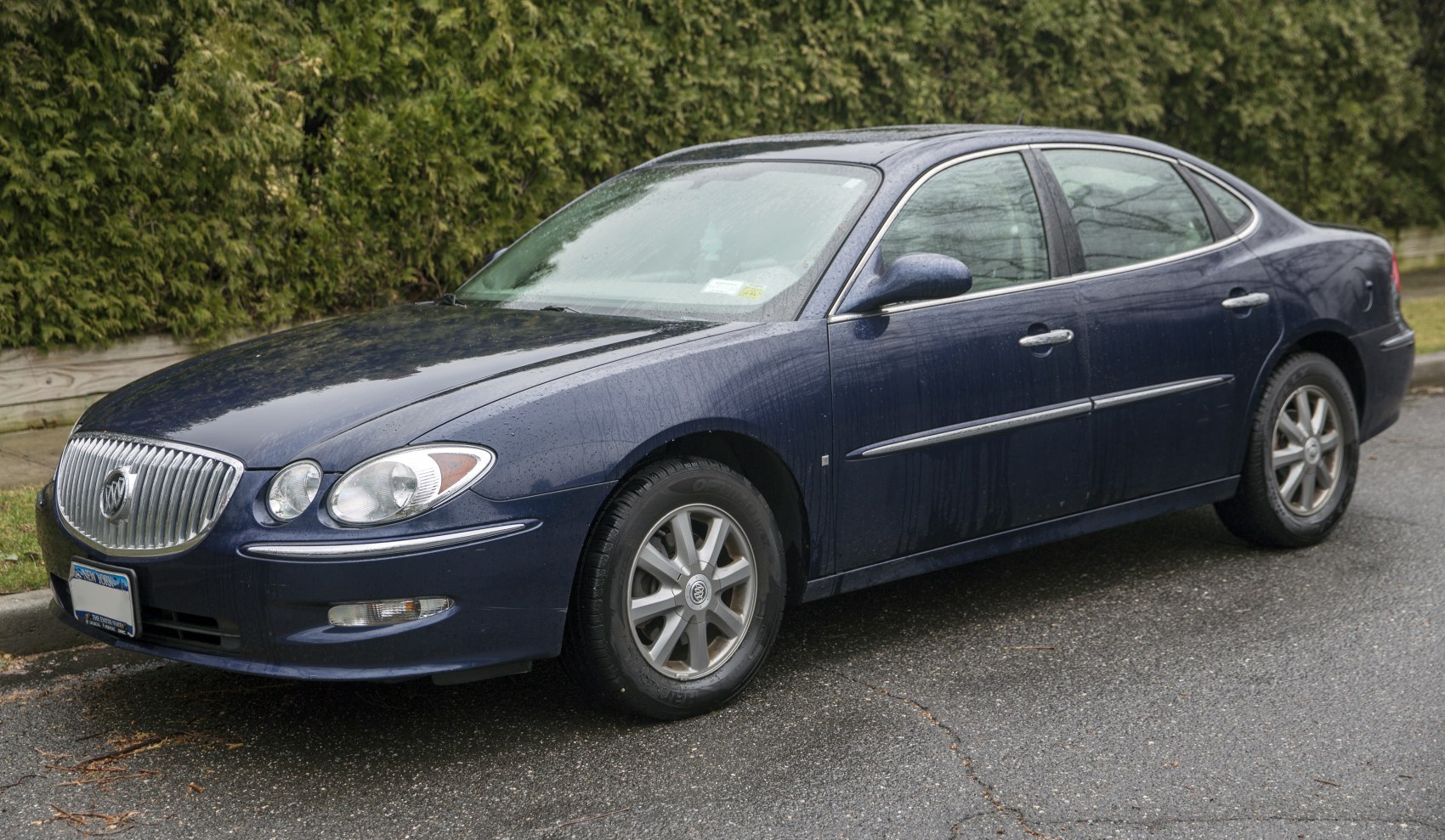 Sedan with chrome grille and alloy wheels, wet surface.