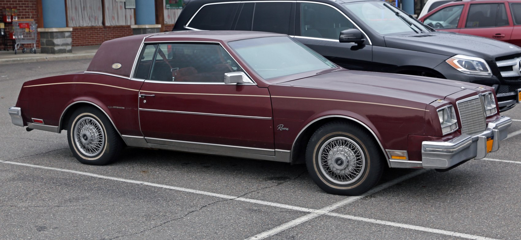 Vintage two-door coupe with vinyl roof and wire spoke wheels.