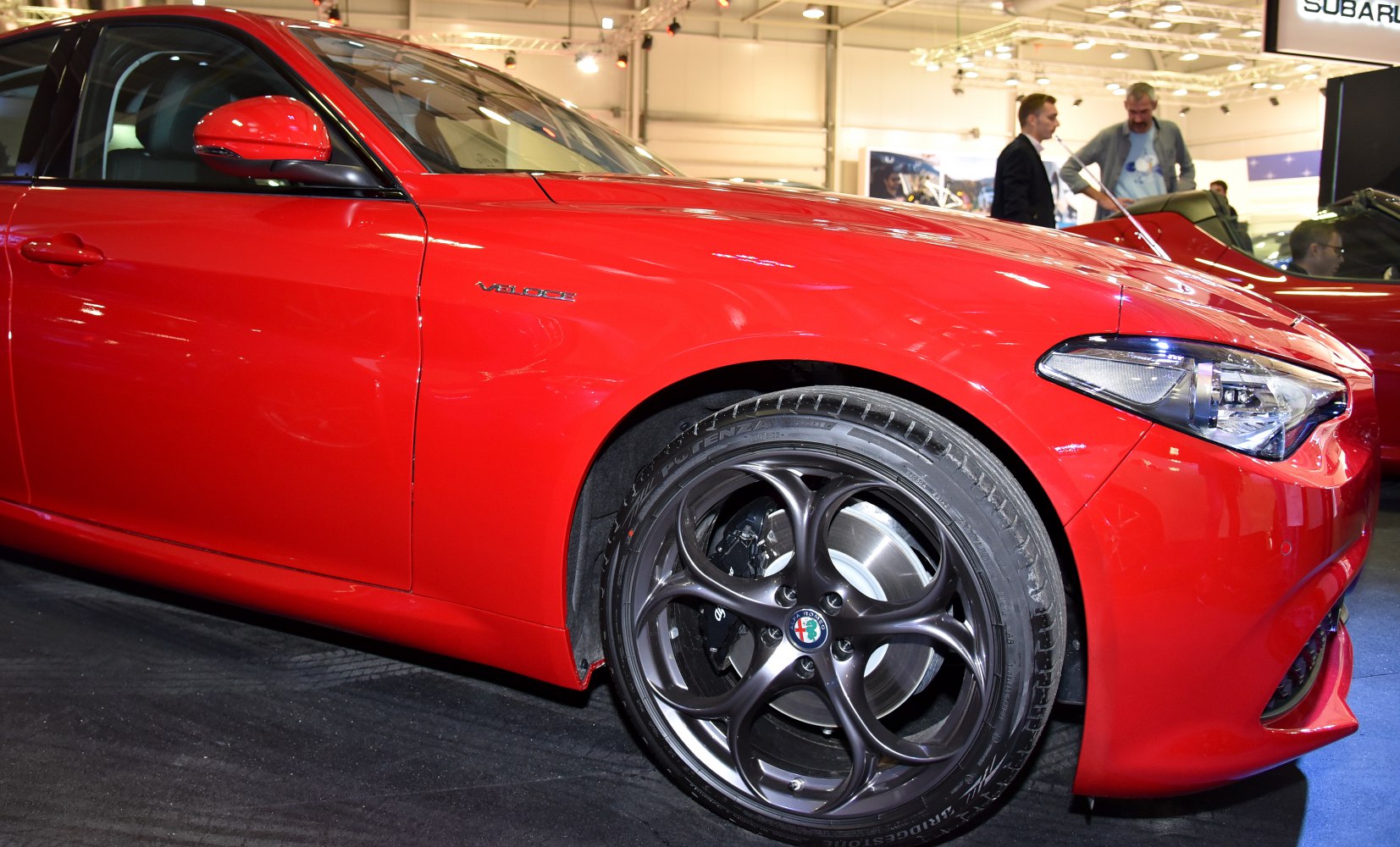 Red car front side with Veloce badge, alloy wheel, and headlight