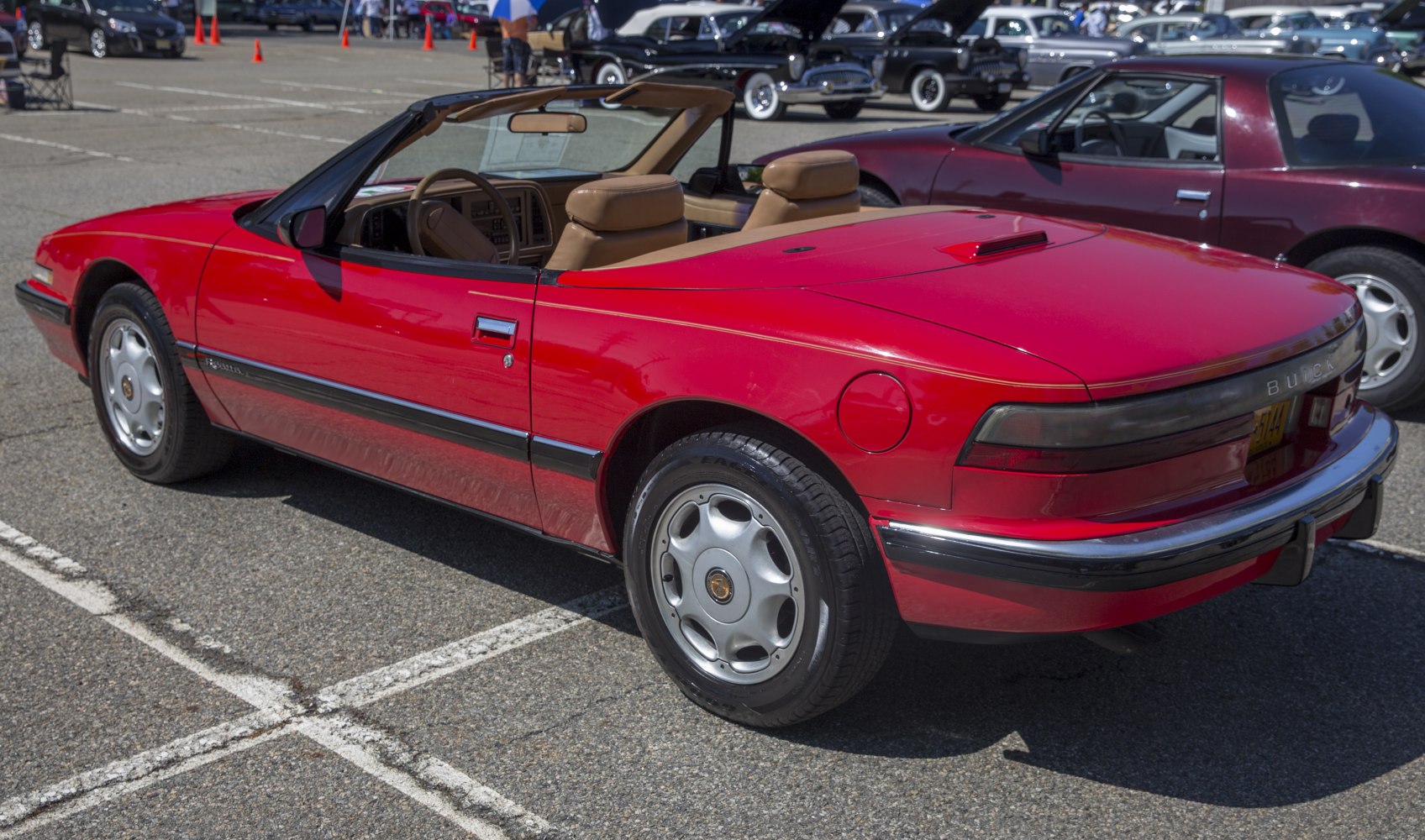 Red convertible with rear side view and visible tan interior seats