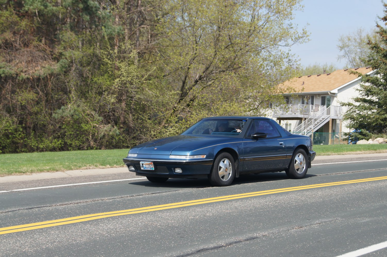 Front side view of a classic 1988 coupe driving on suburban road
