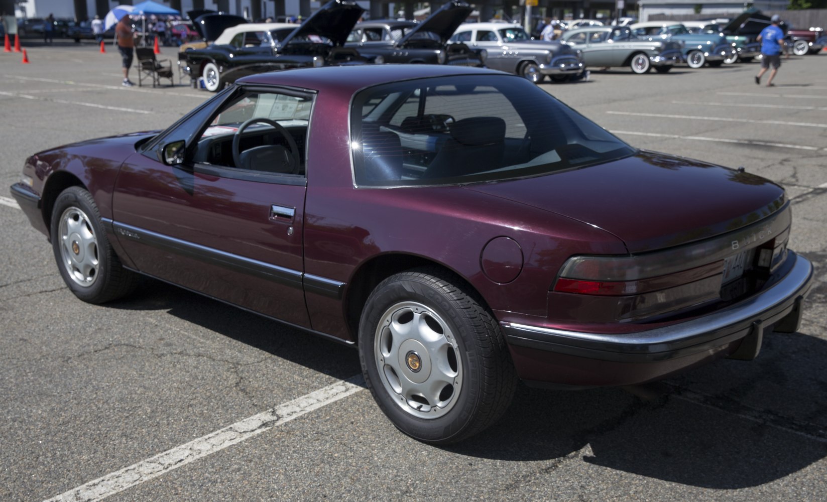 Rear-side view of a vintage coupe with unique rear window and maroon paint