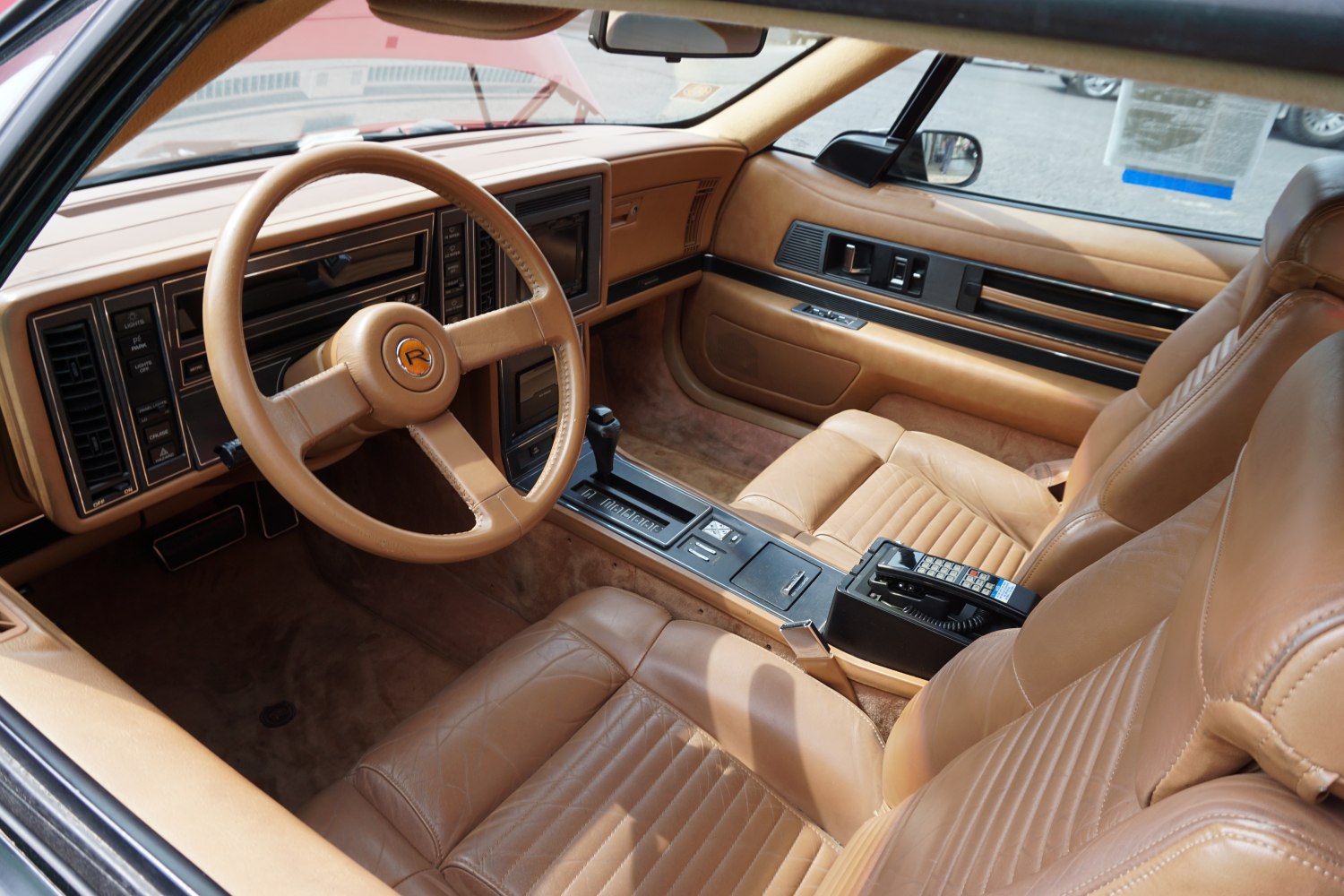 Vintage car interior with tan leather, classic dashboard, and retro phone