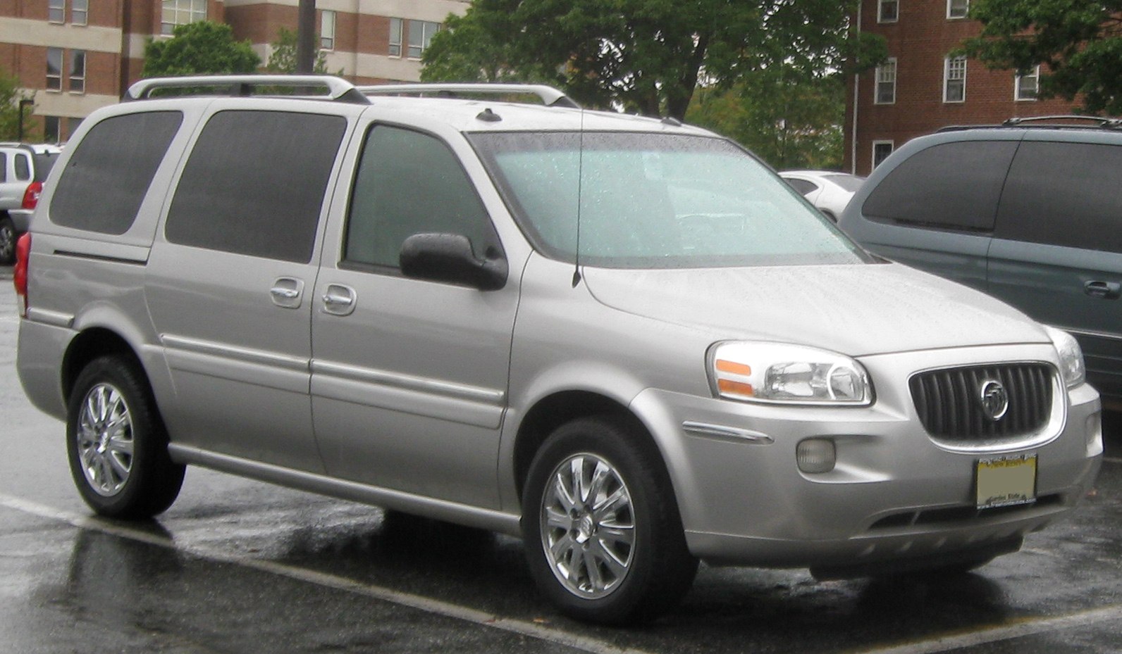 Silver minivan with roof rails and chrome alloy wheels from front-side view