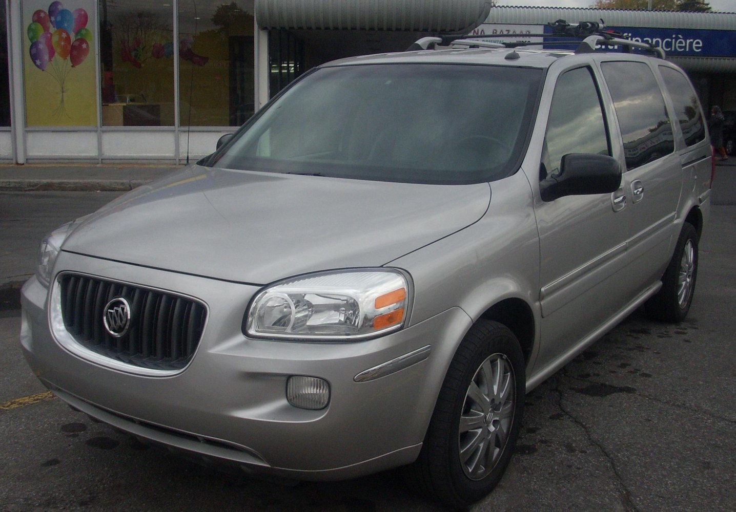 Front side view of silver minivan with distinctive grille and headlights