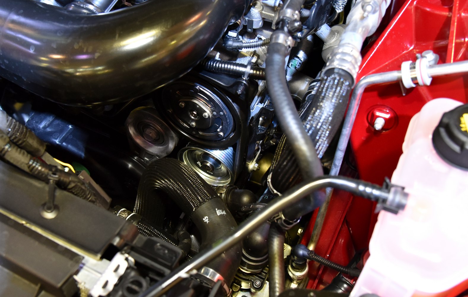 Close-up on engine components with hoses and pulleys