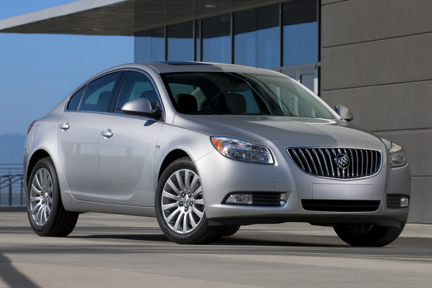 Front-side view of sedan with chrome vertical grille and alloy wheels