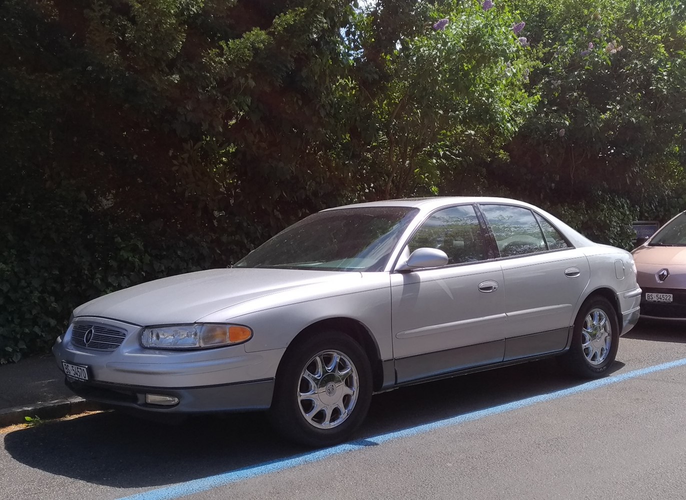 Side profile of sedan with rounded headlights and chrome multi-spoke wheels