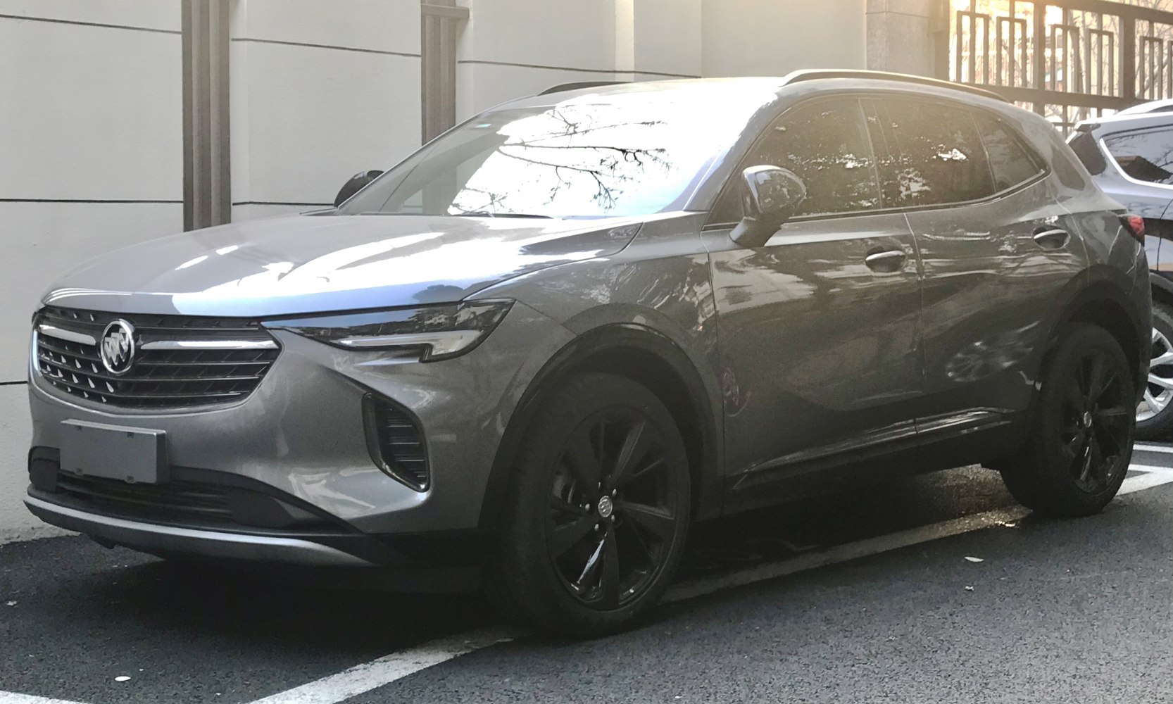 Front side of a grey SUV with black wheels parked.
