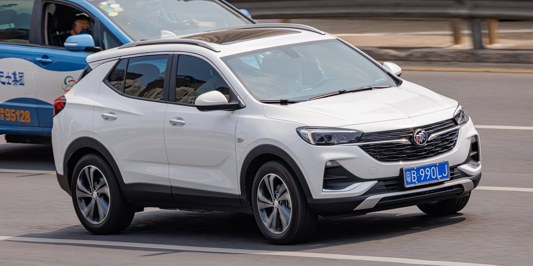 White compact SUV with modern front grille and roof rails in side-front view