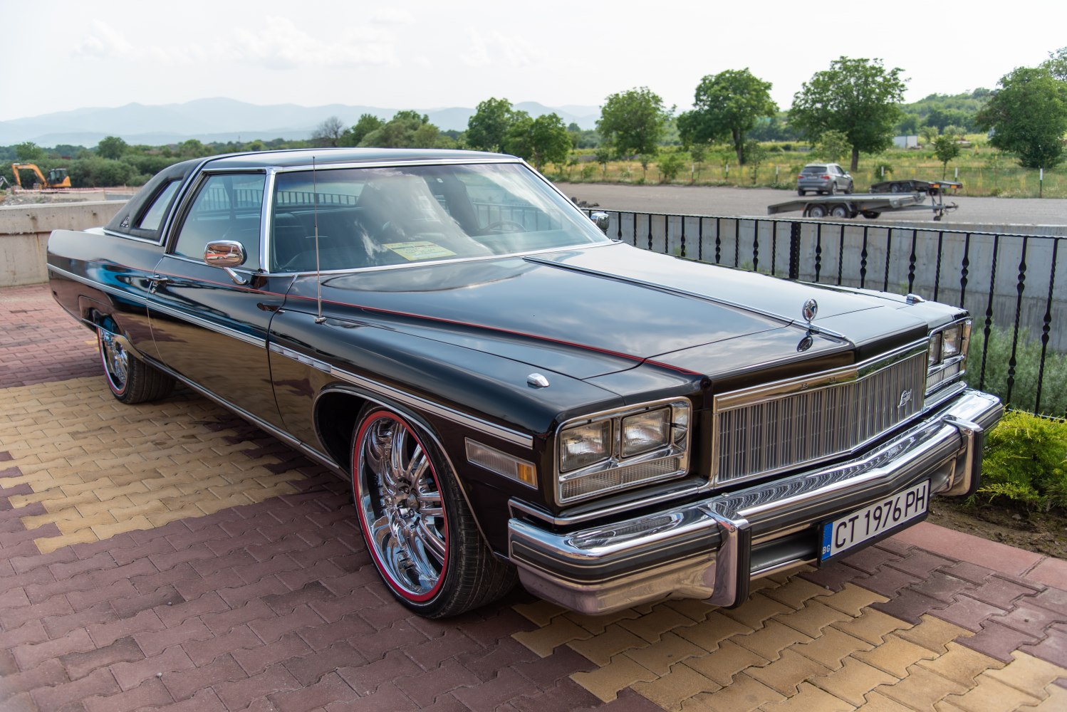 Vintage coupe with chrome bumper, rectangular headlights, and custom rims with red trim.