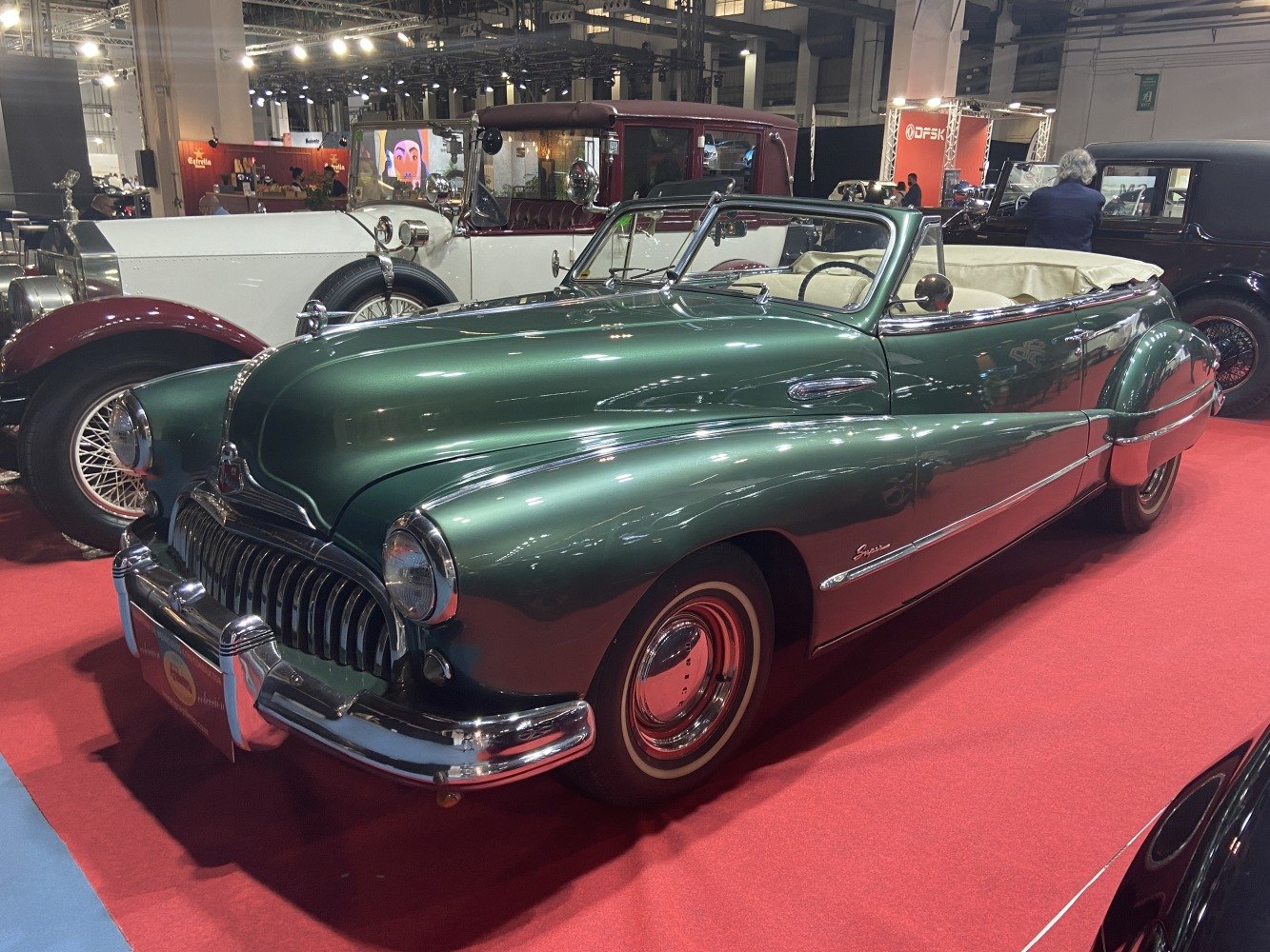 Vintage green convertible with chrome grille and whitewall tires