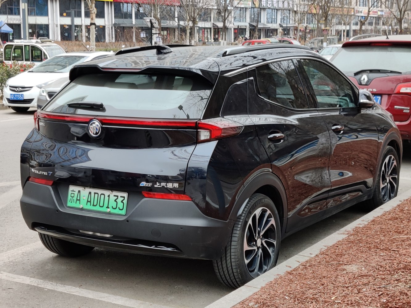 Rear-side view of sleek black electric SUV with roof spoiler and LED tail light