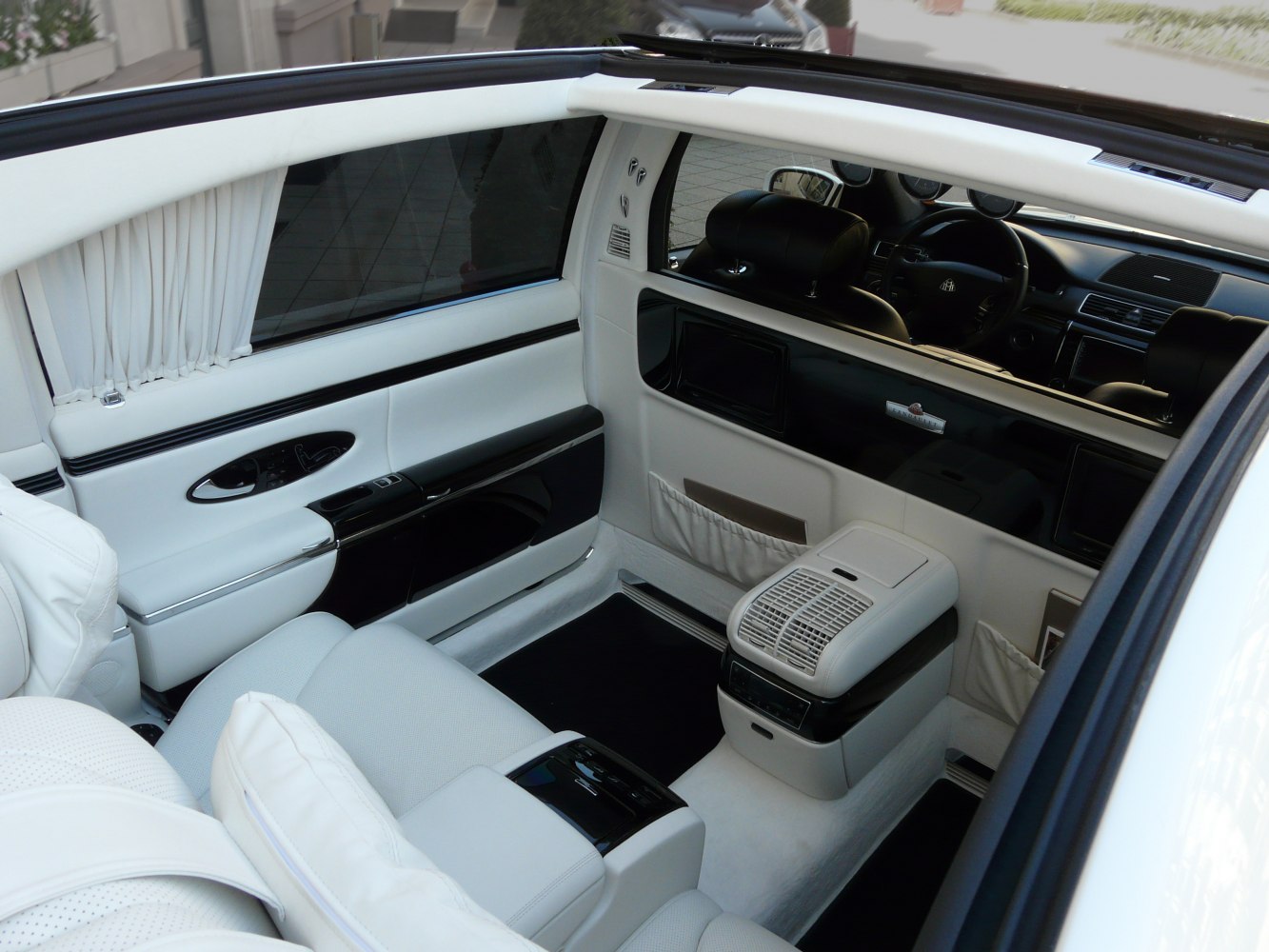 Luxurious white leather rear passenger interior with advanced controls and divider