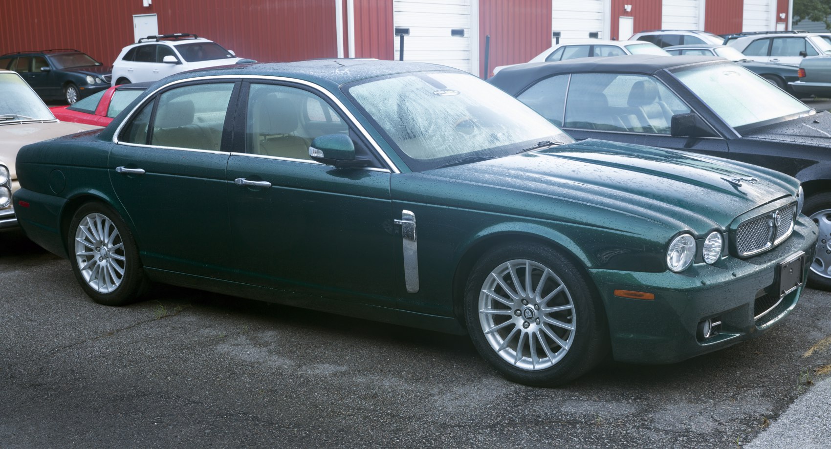 Green luxury sedan side view with chrome trim and alloy wheels