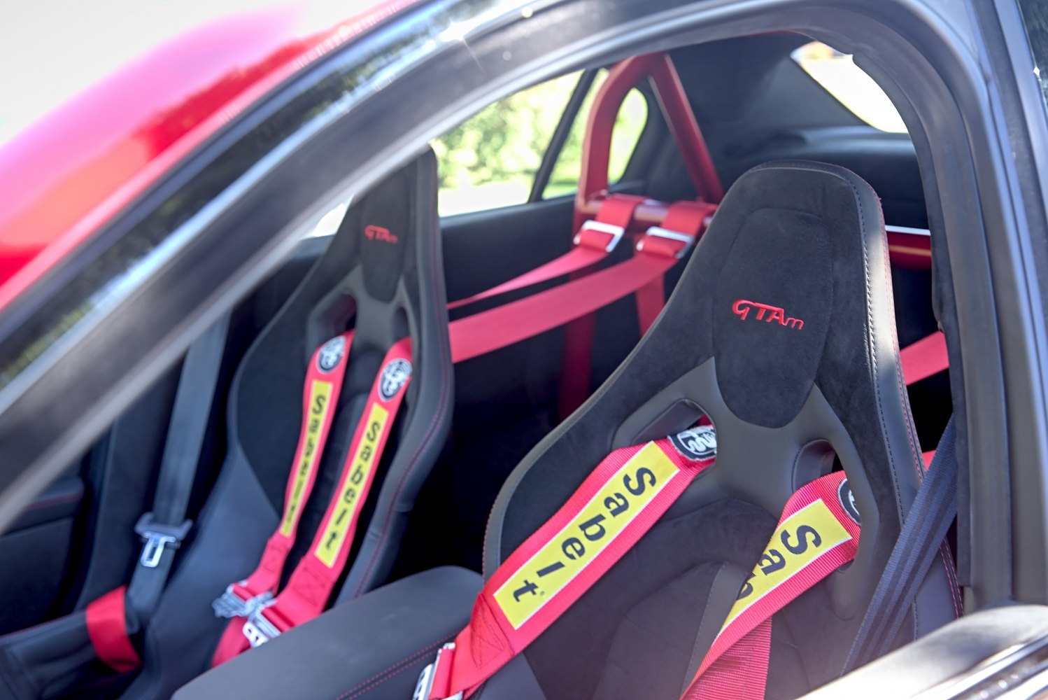 Racing bucket seats with red safety harnesses and roll cage bars