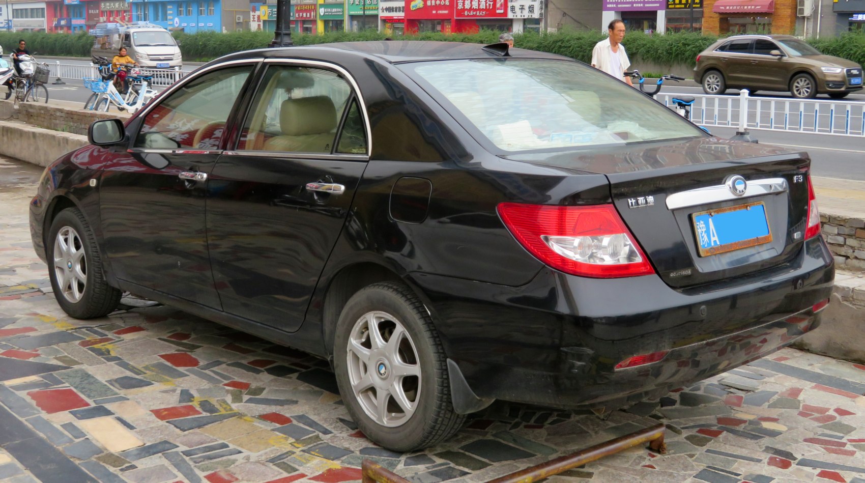 Black sedan rear-side view with taillights and alloy wheels