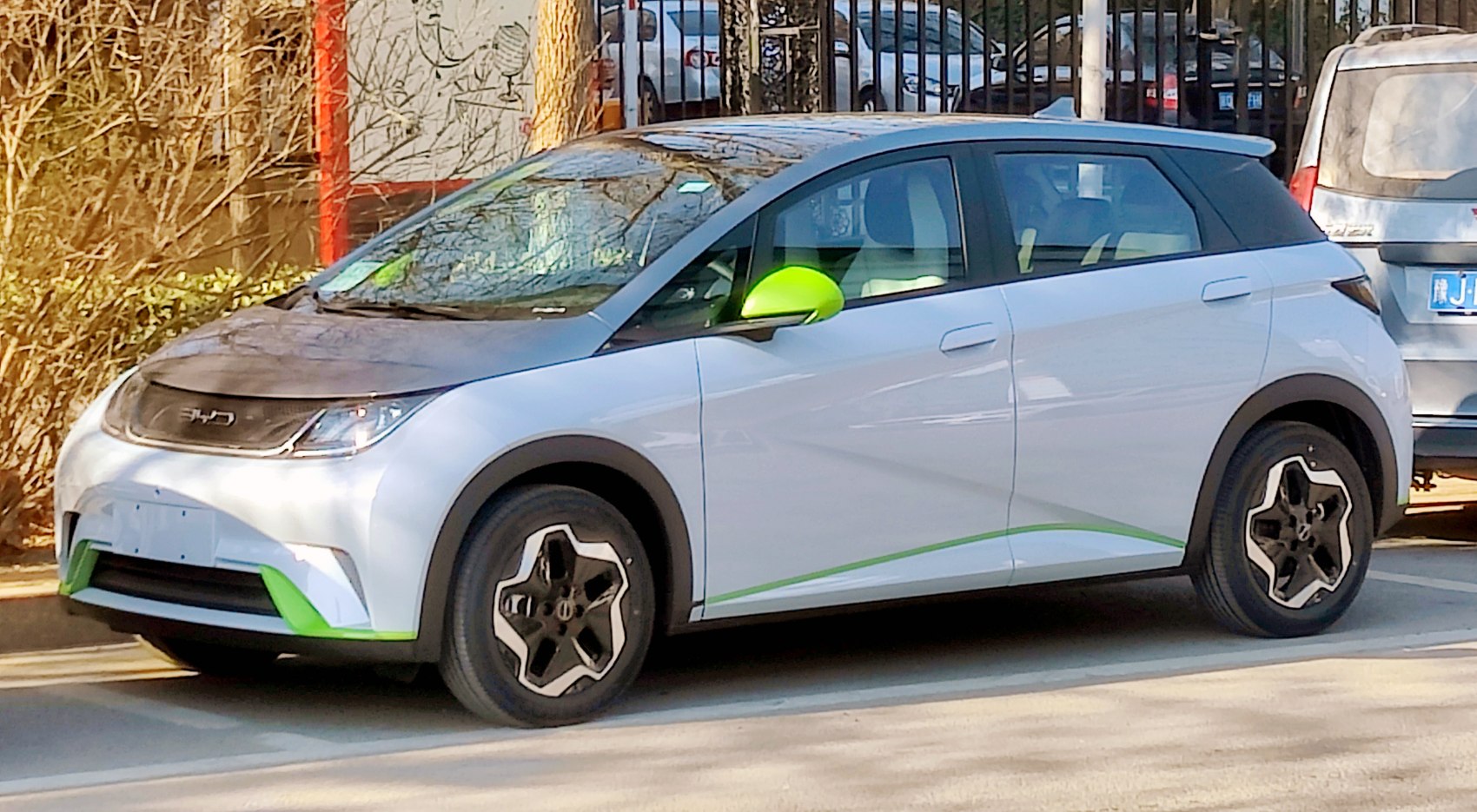 White hatchback with green accents and black roof parked outdoors