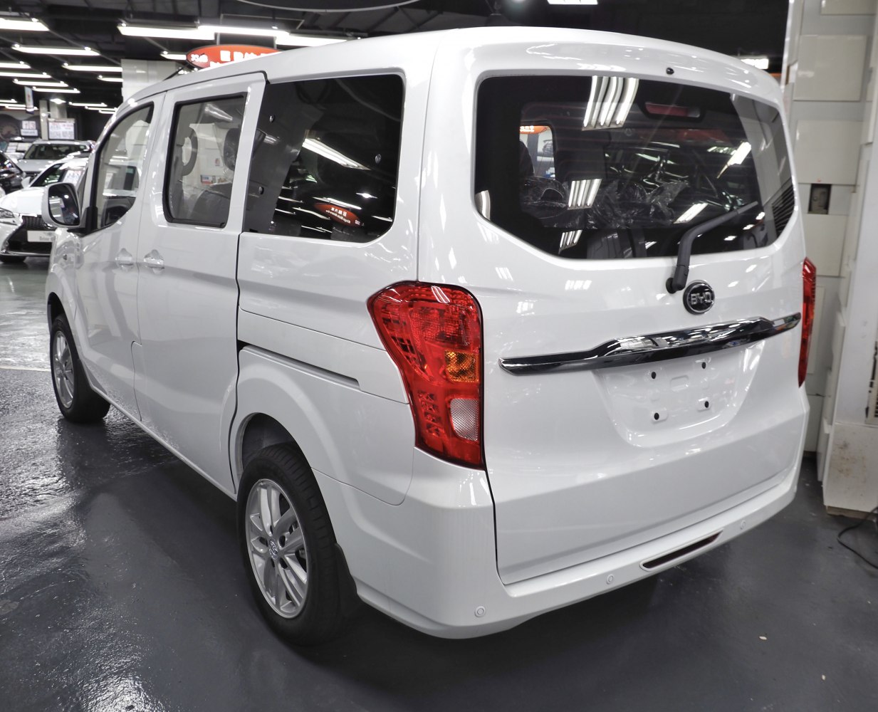 Rear and side view of white electric van with large windows and taillights