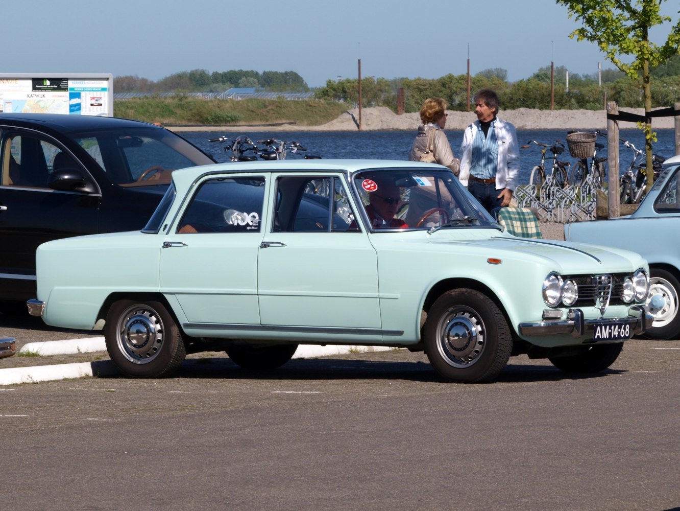 Side view of a vintage sedan with quad round headlights and boxy design.