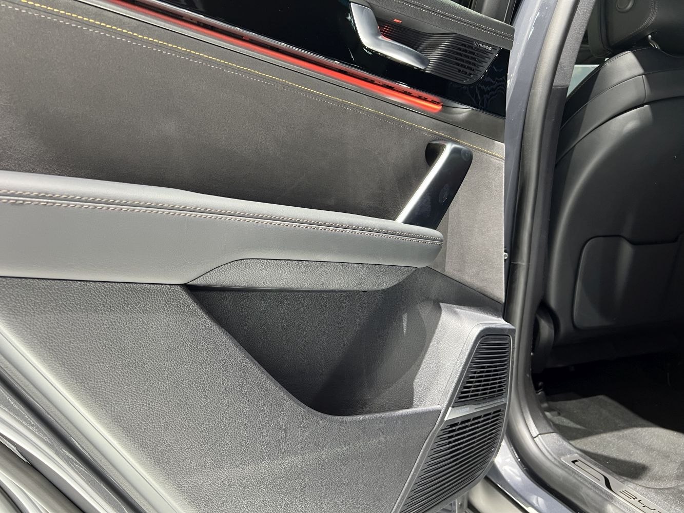 Car door panel with premium stitching and integrated speaker grille