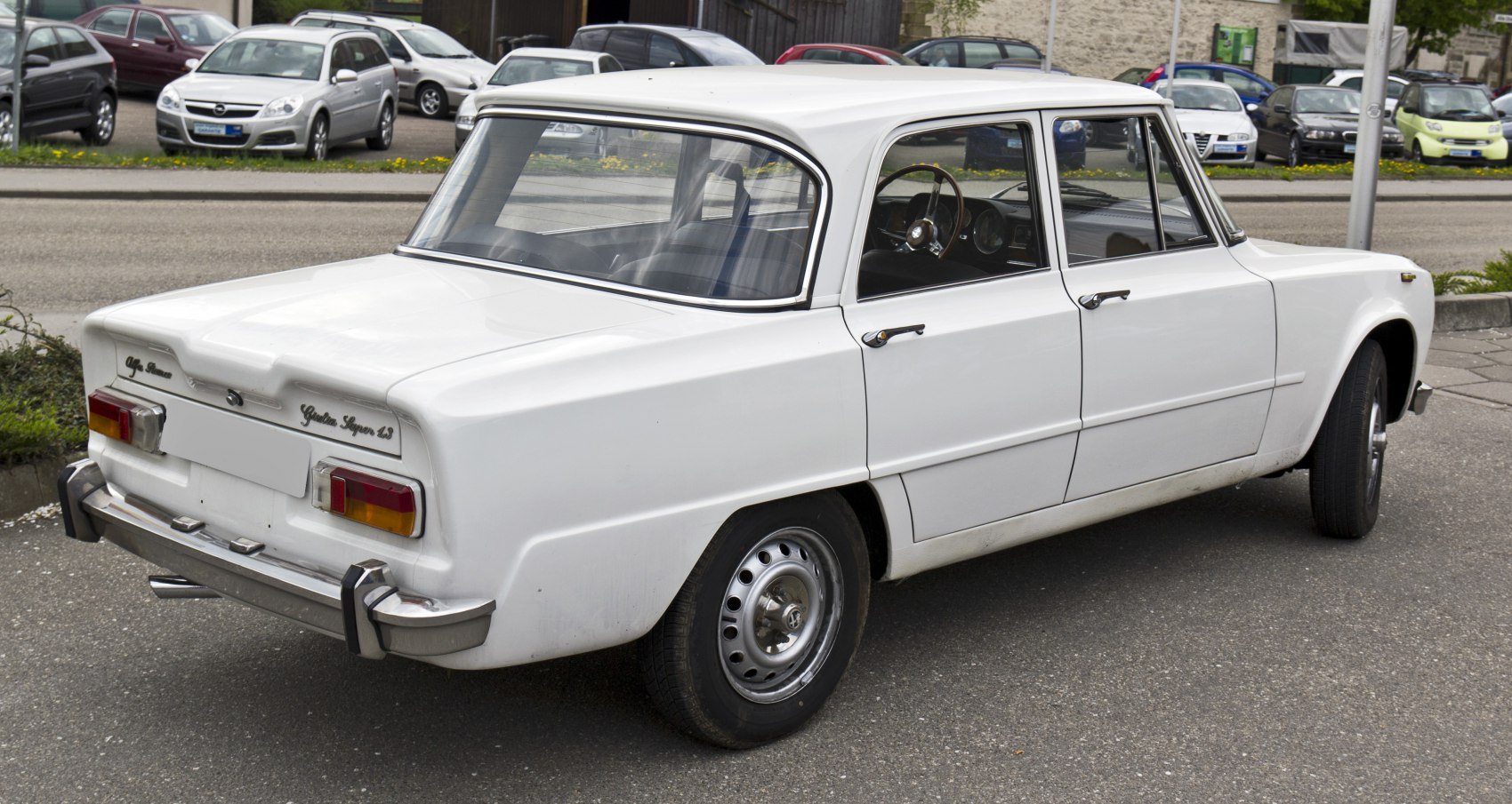 Classic white car's rear with vintage taillights and chrome bumper.