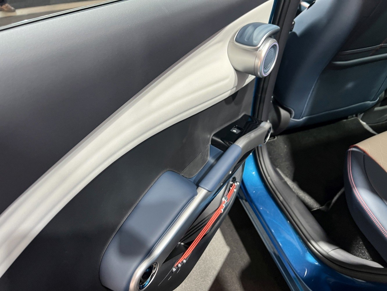 Modern car door panel with integrated speaker, handle, and armrest.