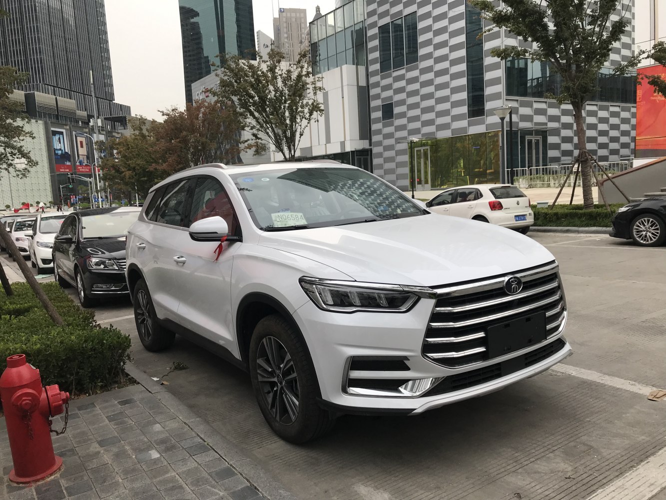 Front grille and LED headlights of a white SUV parked on a city street.