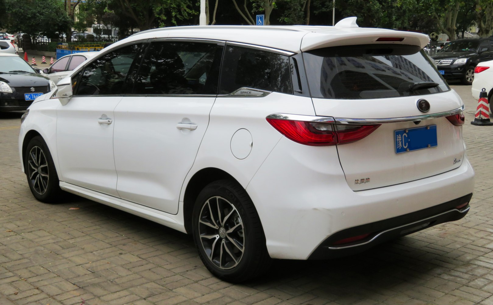 Mid-size white MPV with rear spoiler and alloy wheels