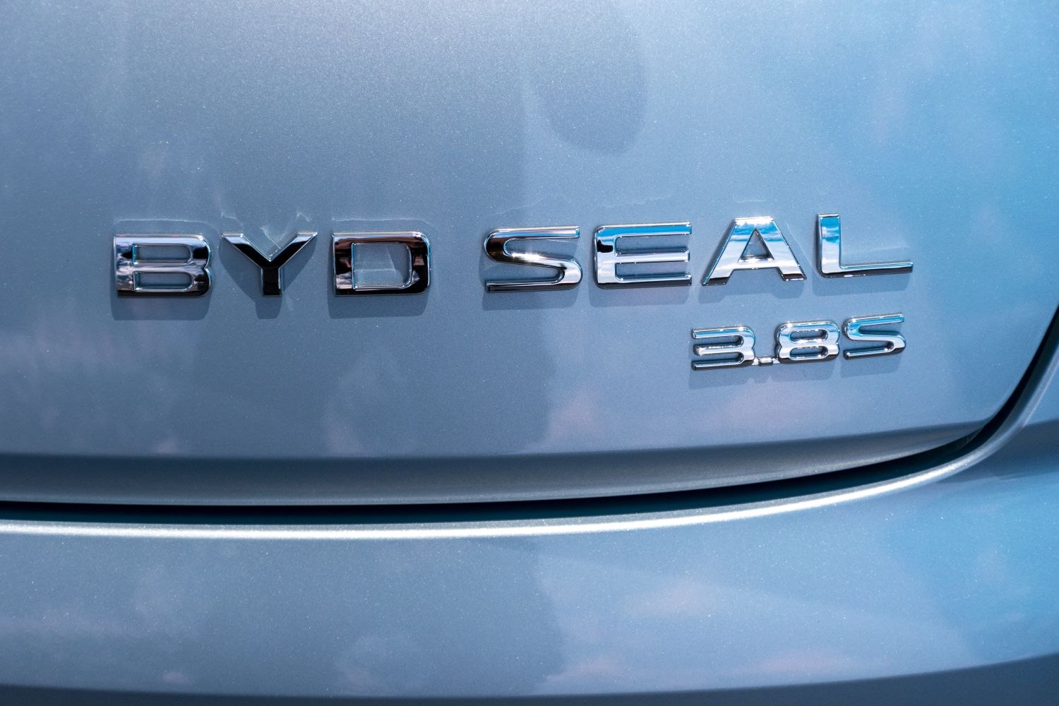 Close-up of BYD Seal 3.85 chrome emblem badge on light blue surface
