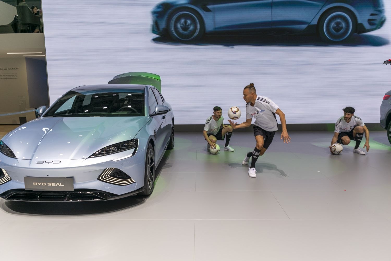 Front view of sleek electric sedan with soccer players holding balls
