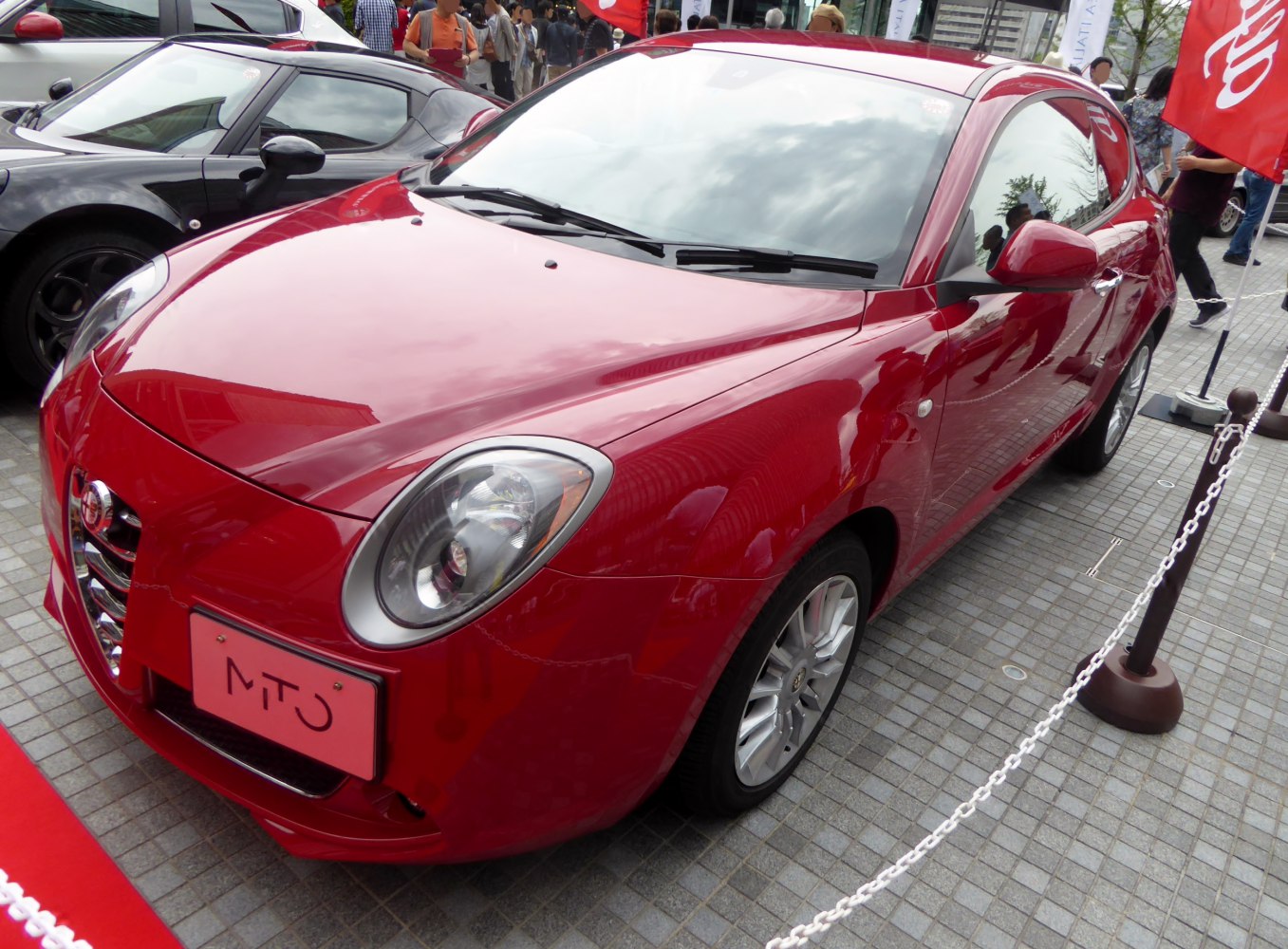 Close-up front angle view of sporty red compact hatchback with distinctive headlights.