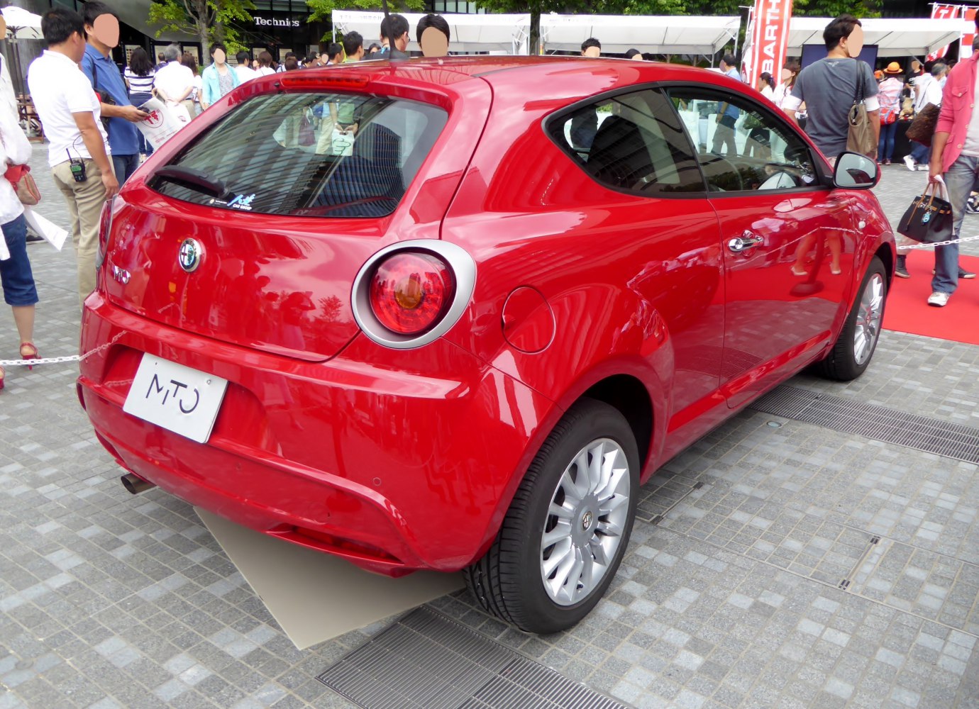 Red compact hatchback with circular rear lights and alloy wheels