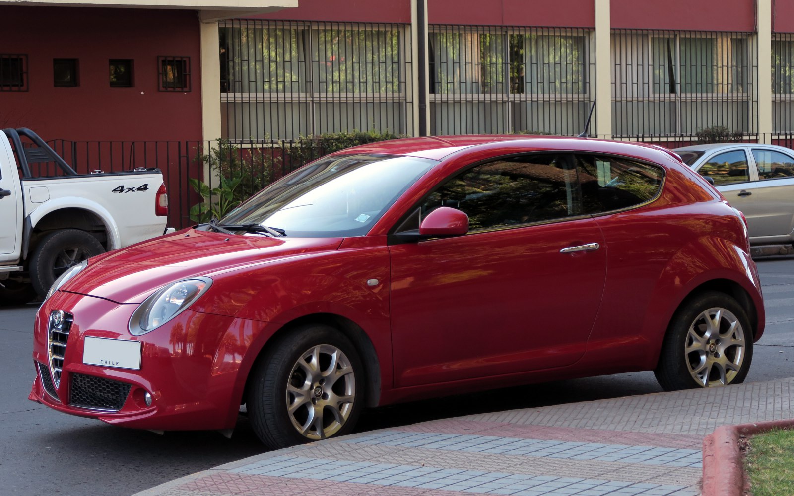 Red compact hatchback with sleek design and alloy wheels side view