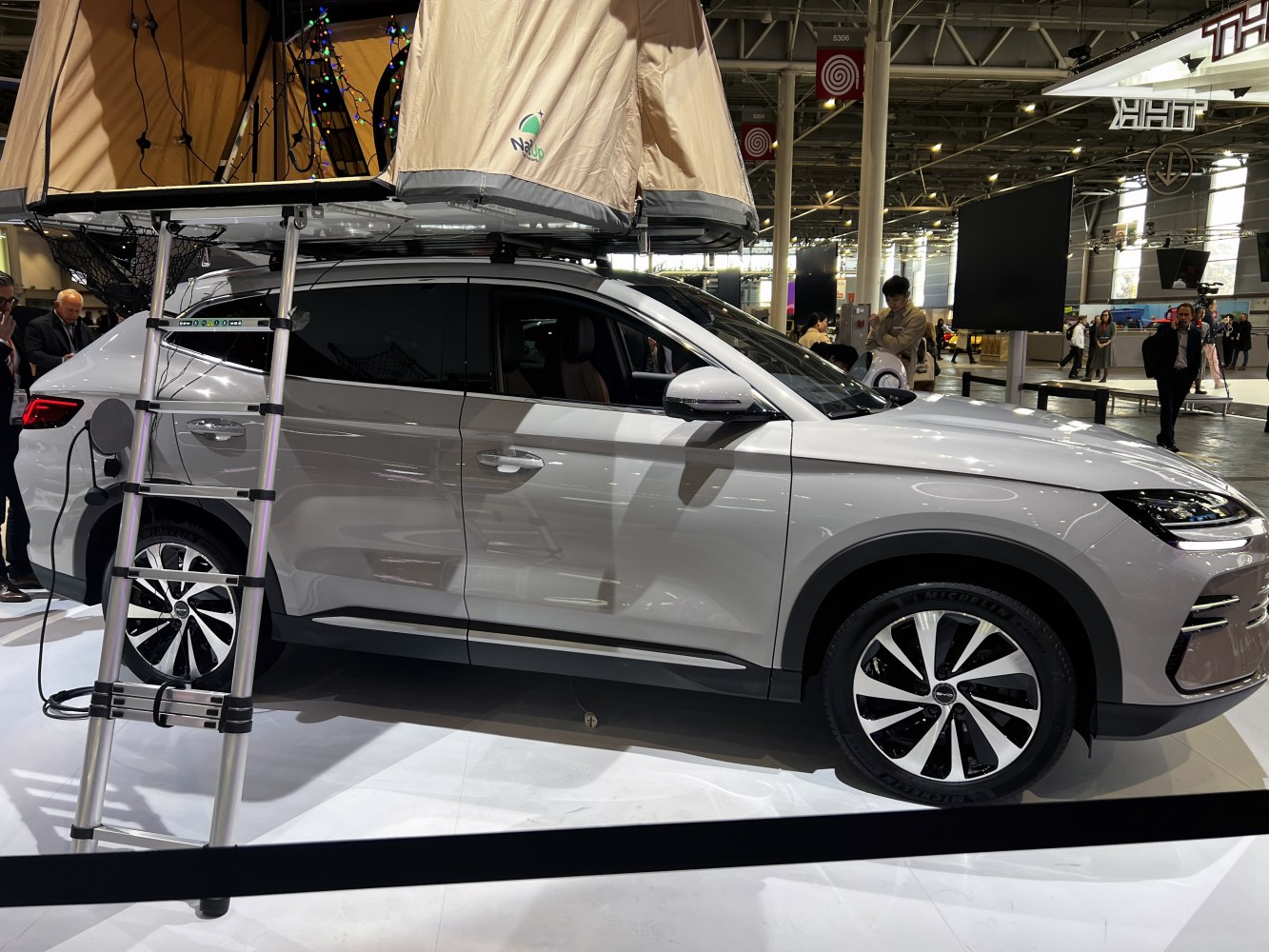 Electric SUV with rooftop camping tent and ladder
