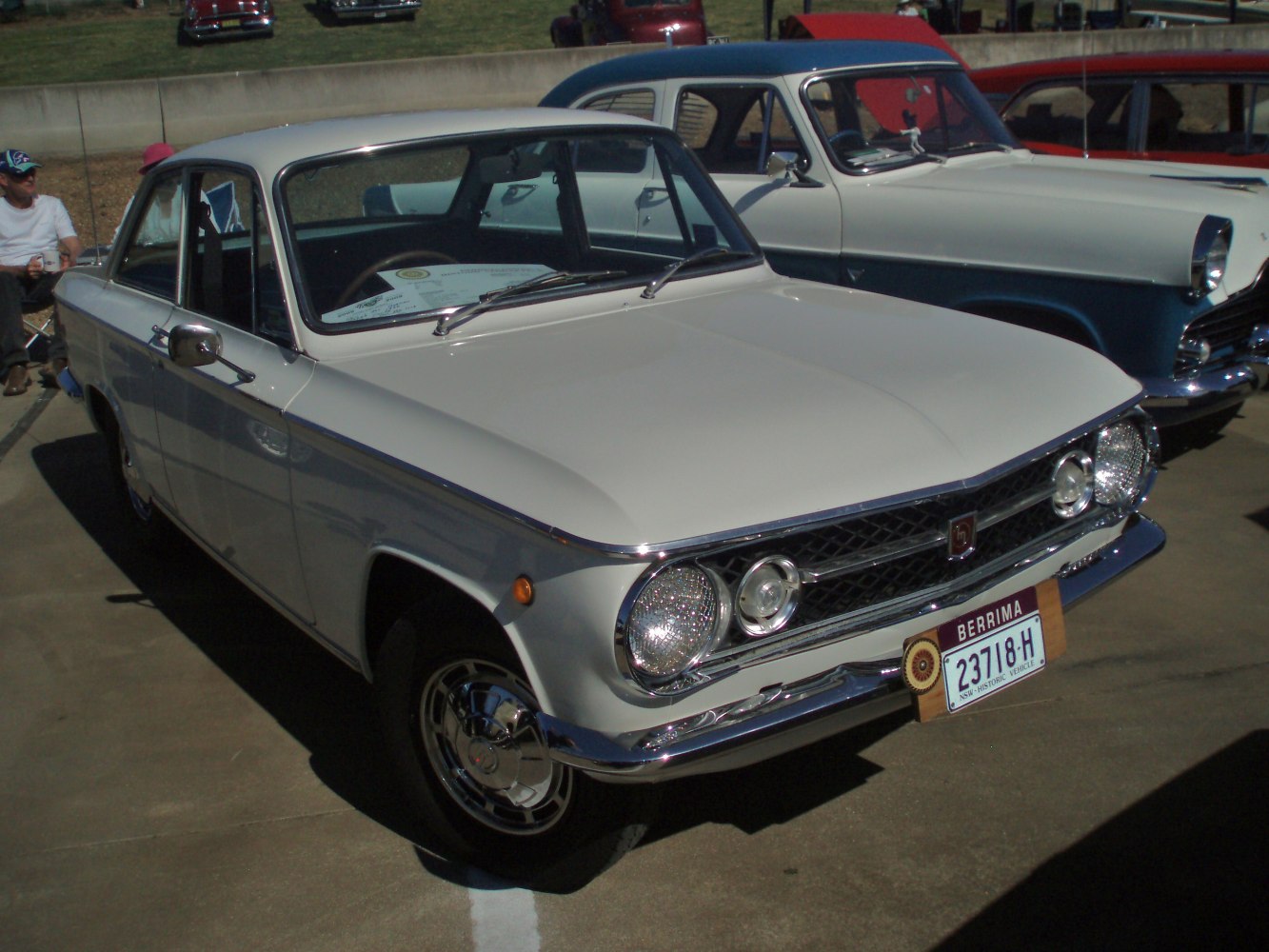 White vintage two-door coupe with round headlights and chrome grille.