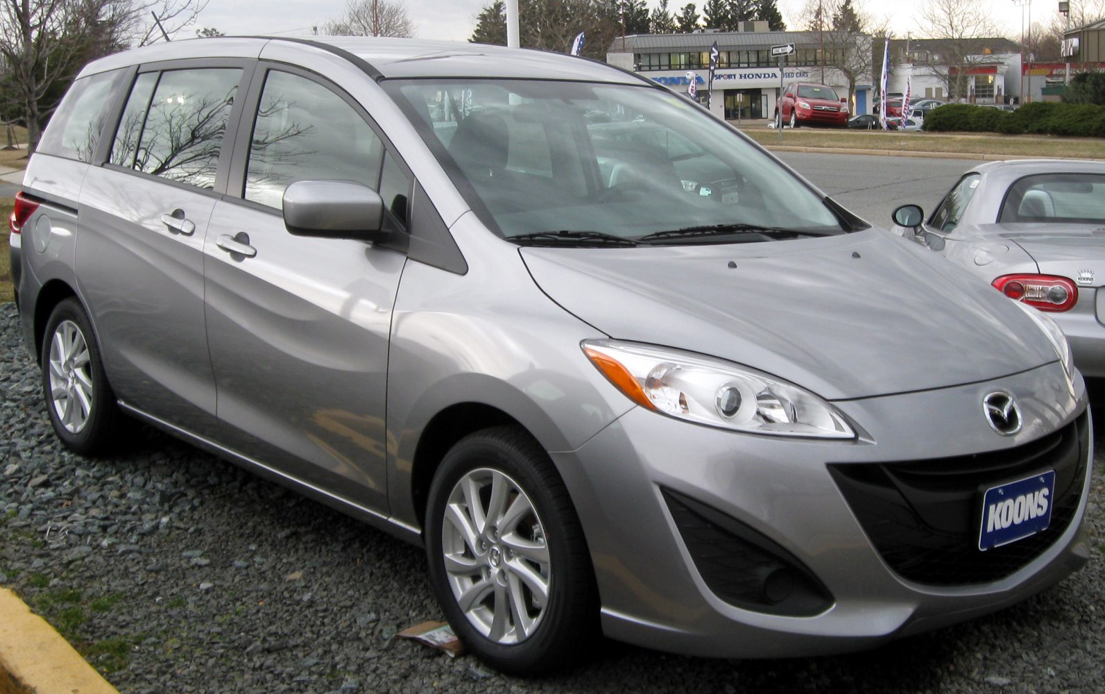Front side view of a 2010 model minivan with sleek headlights and silver body.