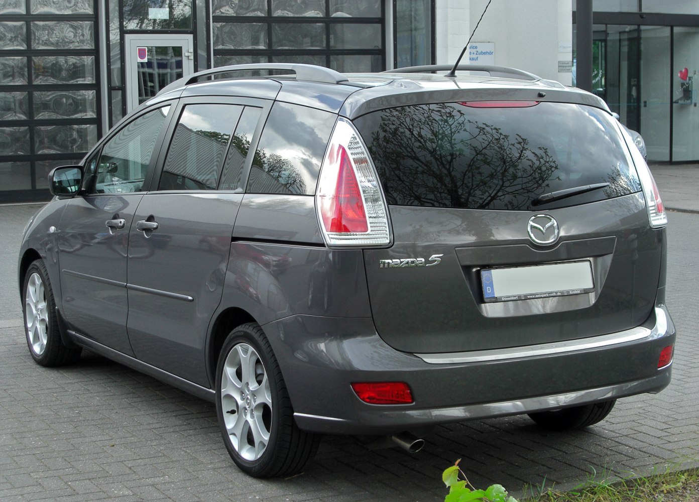 Rear view of a compact MPV with vertical tail lights and roof rails.