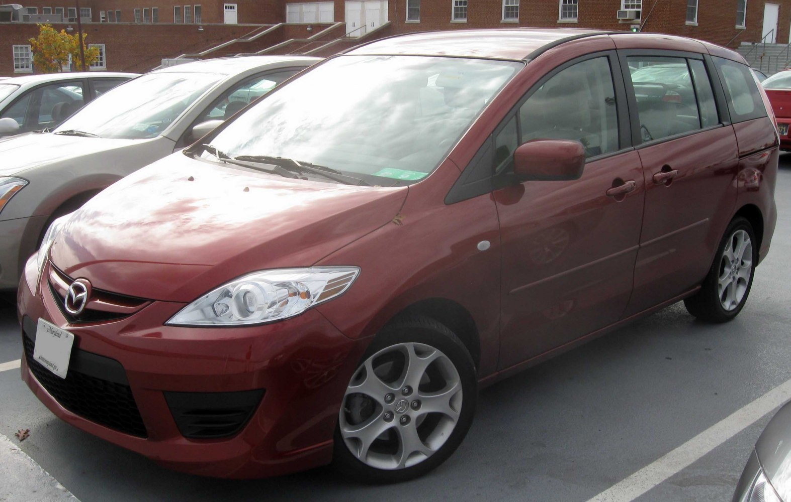 Front and side view of red minivan with alloy wheels and sharp headlights