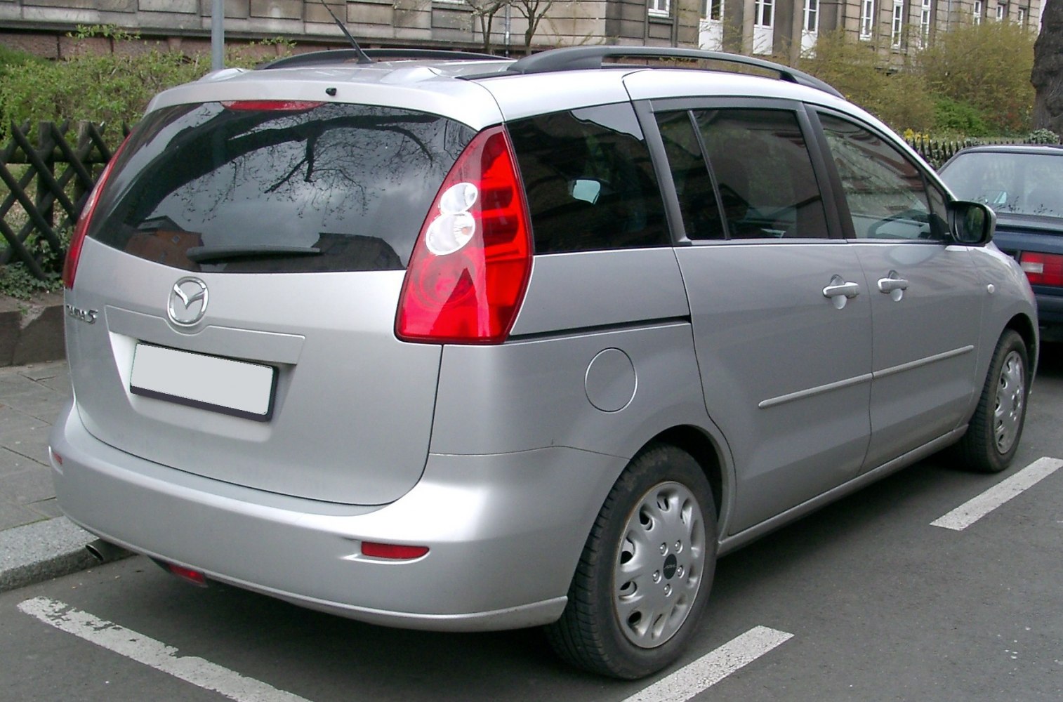 Silver compact MPV rear side with vertical taillights and roof rails