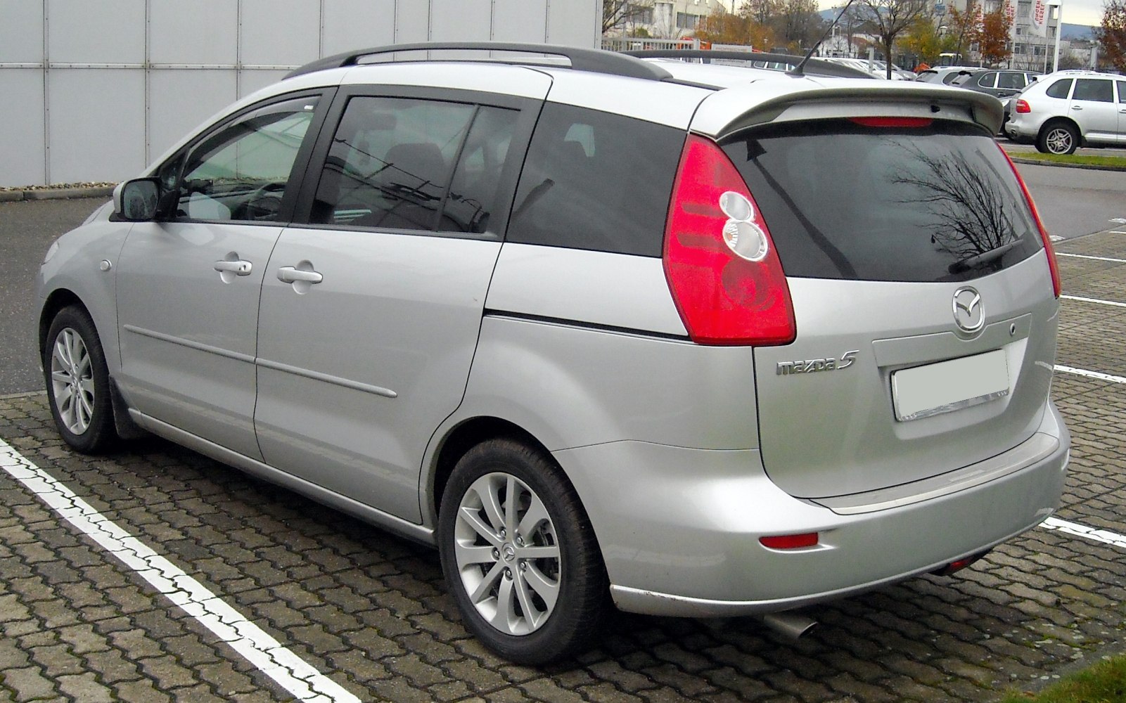 Silver compact minivan rear three-quarter view with roof rails and distinct taillights