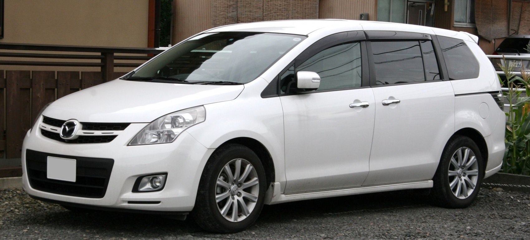 Front side view of white minivan with alloy wheels and headlamps