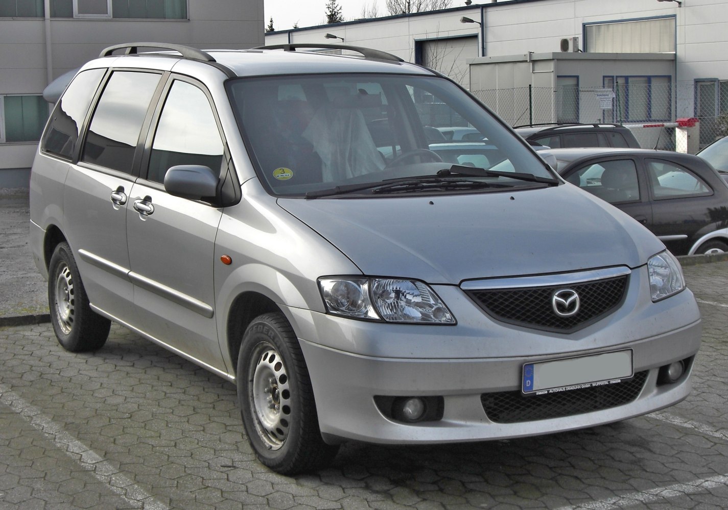 Silver minivan front side view with roof rails and clear headlights