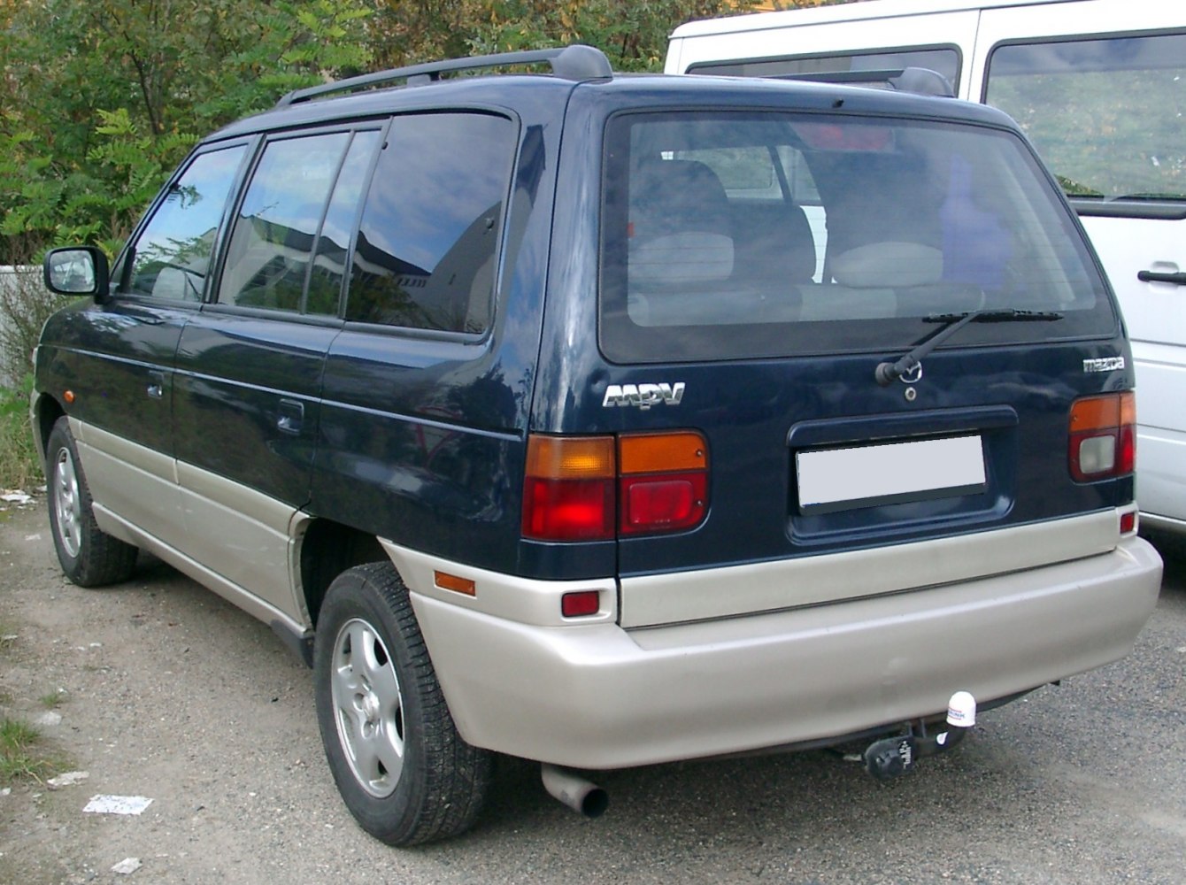 Rear-side view of two-tone minivan with distinctive taillights