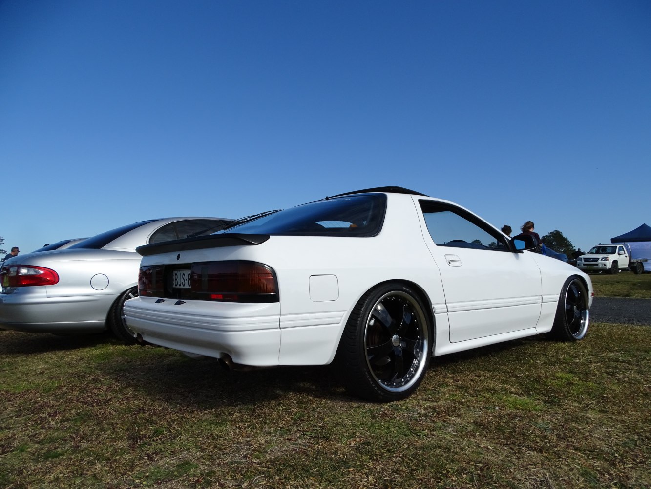 White sports coupe rear profile with black rims and spoiler