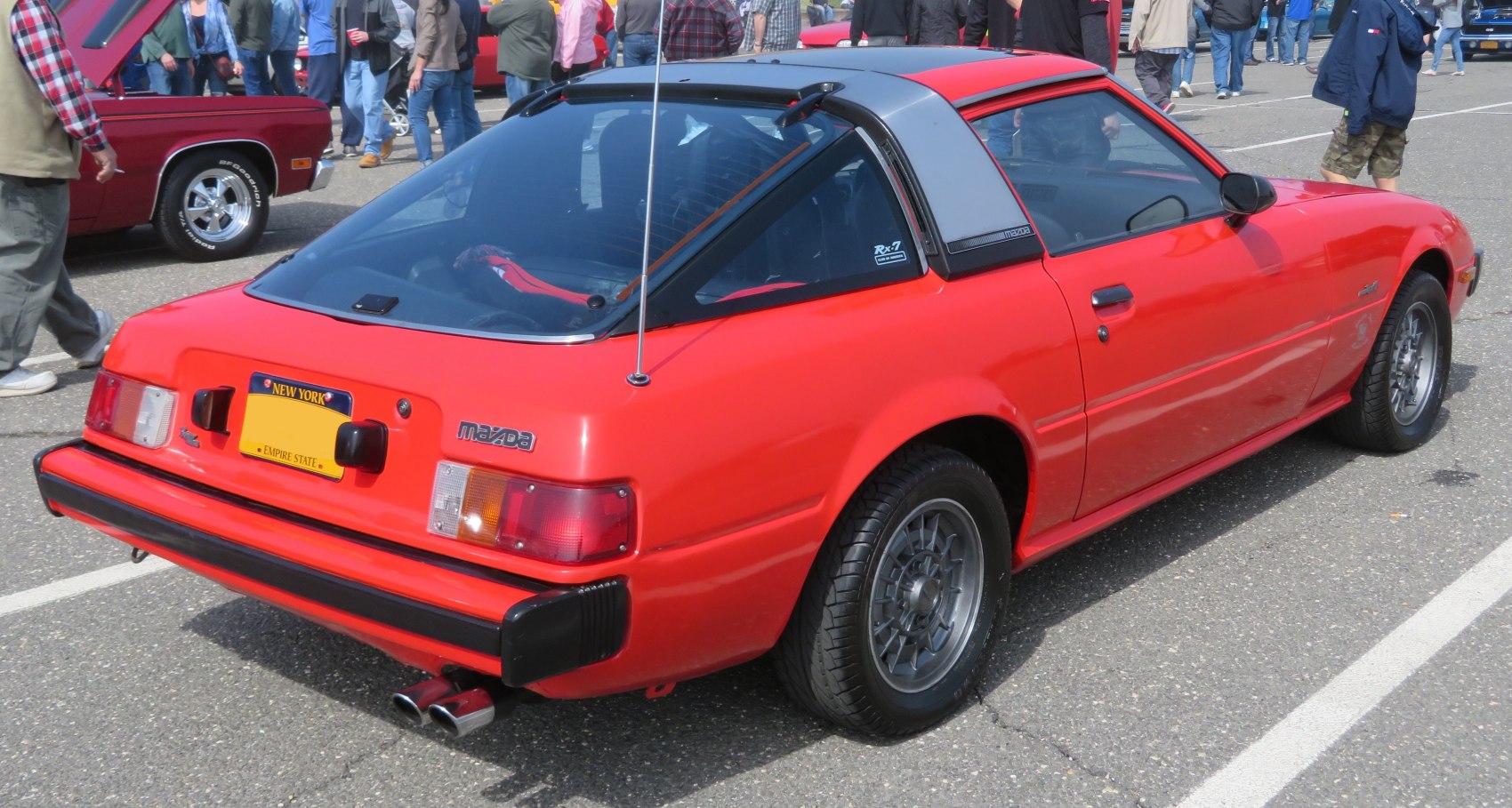Rear and side view of red sports car with hatchback and T-top roof.