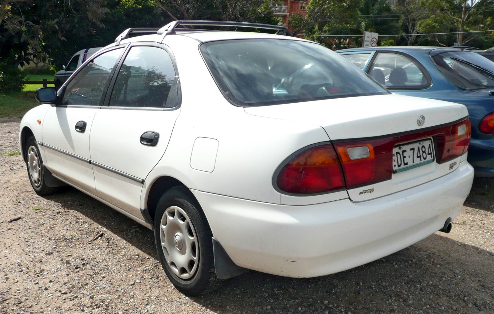 Rear side and tail lights of white sedan with roof rack