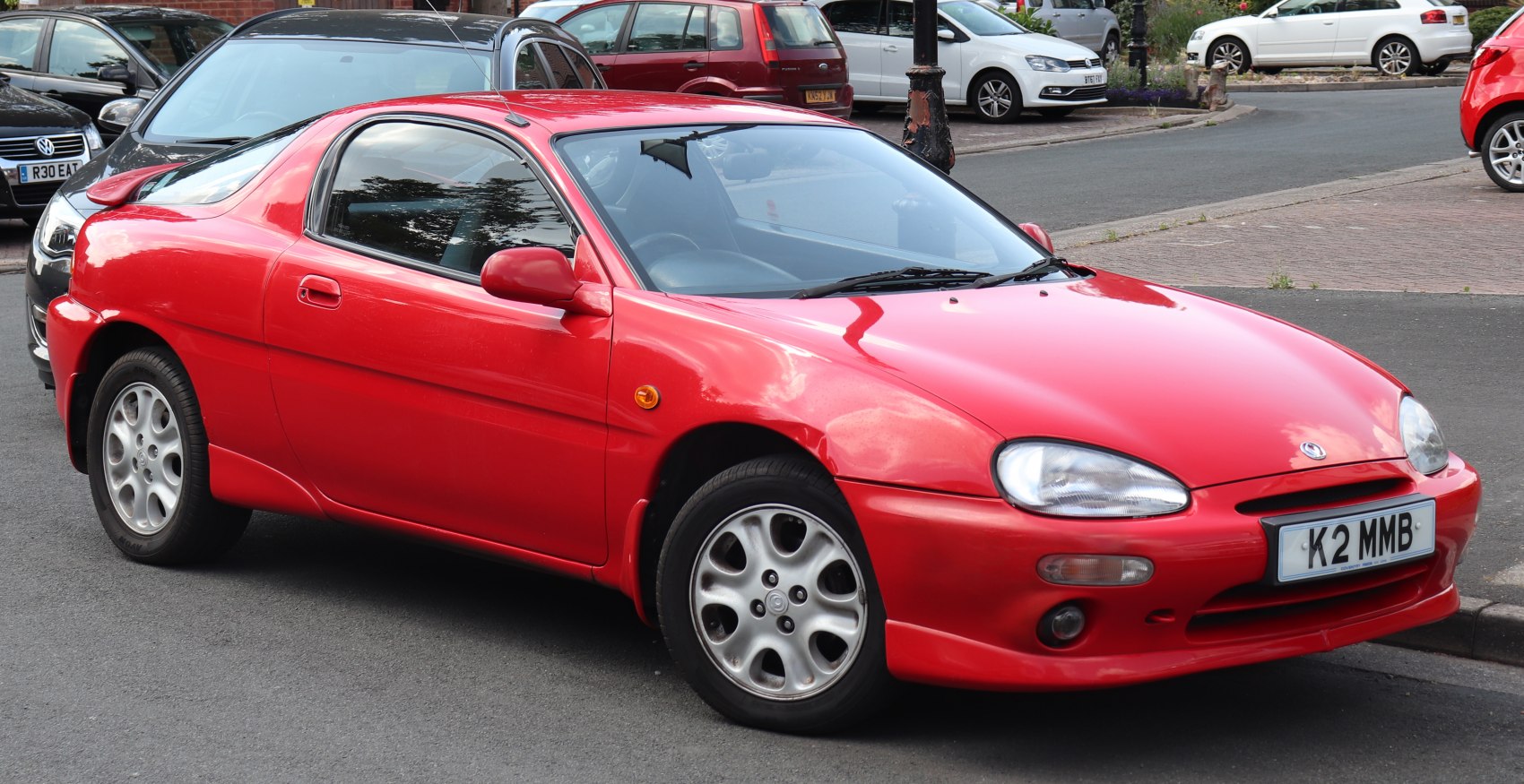 Red compact sports coupe with rounded headlights and aerodynamic design