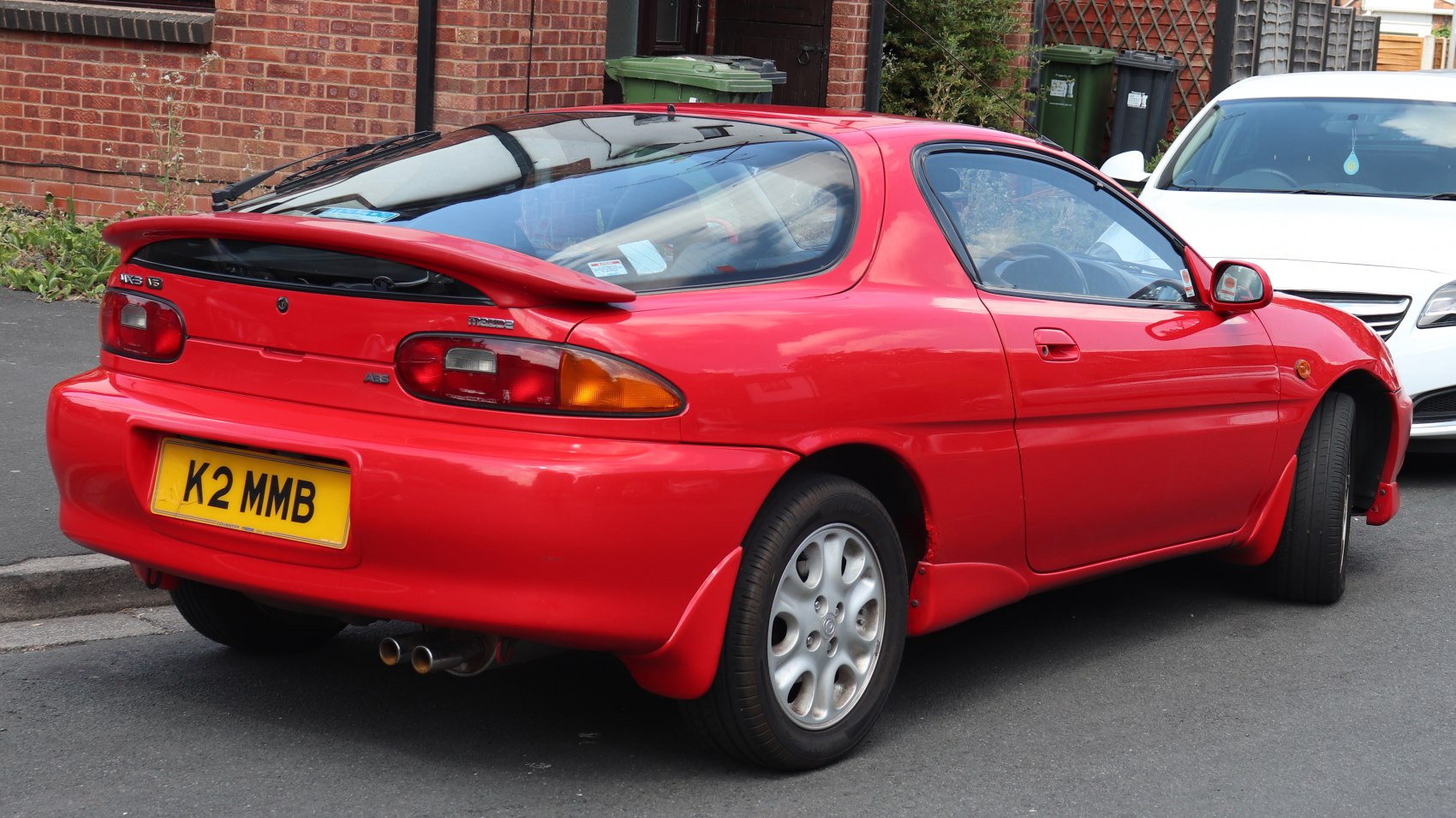 Rear side view of sporty coupe with rounded taillights and rear spoiler